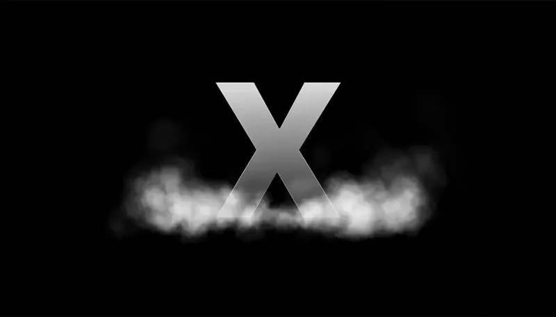 A large silver letter "X" standing against a black background, with a low bank of soft white fog drifting across its base.